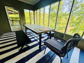 Outdoor dining table on large screened in porch overlooking the lake.