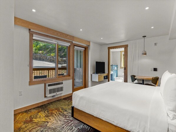 A bright and spacious bedroom with natural light streaming through large windows, offering a peaceful retreat surrounded by nature.