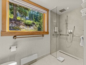 A modern and accessible bathroom featuring elegant finishes and a window that frames lush greenery, providing a tranquil backdrop.