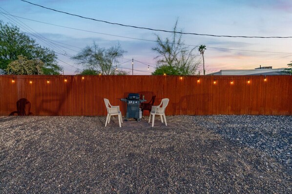Fully fenced backyard area with grill and outdoor seating