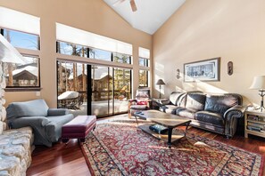 Living room featuring a vaulted ceiling, large flat screen TV, gas fireplace, and access to the private balcony.