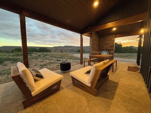 Back patio with comfy seats, fire pit, and dining table with benches