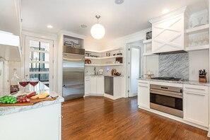 Experience this modern kitchen with stainless steel appliances, marble countertops, and open shelving—perfect for cooking and gathering.