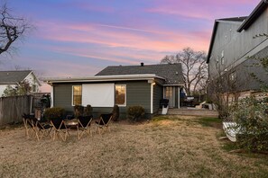 Enjoy the inviting backyard, featuring a fire pit, hammock, and an outdoor theater setup perfect for family fun and relaxation.