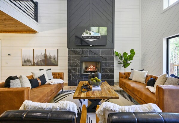 The warm and cozy living room invites you to relax with plush seating, a tall fireplace, and thoughtful touches for a perfect gathering spot.