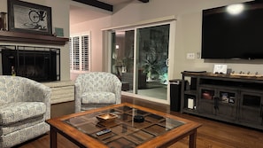 Living room with courtyard access through large sliding doors. 75" Smart TV.