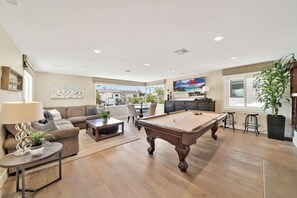 Living room with large screen tv, pool table, game table and peekaboo ocean view.