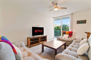 Cozy living space with plush couch, smart TV, AC, and balcony.