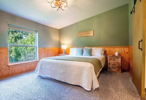 Relax in the serene master bedroom, featuring a king bed, soft lighting, and direct access to a luxurious ensuite bathroom through a charming barn door