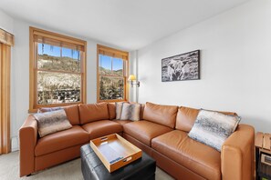 Living area featuring a mounted TV over a gas fireplace, queen sleeper sofa, and balcony access.