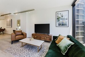 Chic and cozy living area with a blend of modern and classic elements, including a marble-top coffee table, a rich leather armchair, and a striking green velvet sofa.