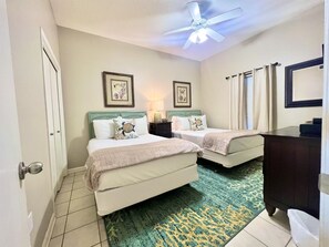 Guest bedroom: Two full beds, beach accents, and warm neutral tones.