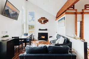 The living room is the epitome of comfort and relaxation, featuring a plush sofa, a Smart TV, views of Boulder Bay and an abundance of natural light that pours in through the large windows along with a wood burning fireplace.