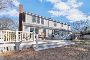 The expansive deck extends the living space outdoors, featuring a dining area and grill, perfect for enjoying sunny afternoons and tranquil evenings in this spacious backyard retreat.