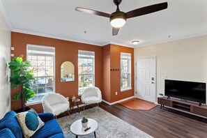 Bright living space with sectional sofa, 50" smart TV, and hardwood floors.