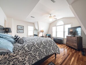 Luxurious master bedroom with a king-size bed, vaulted ceilings, and a large TV for ultimate comfort and relaxation.