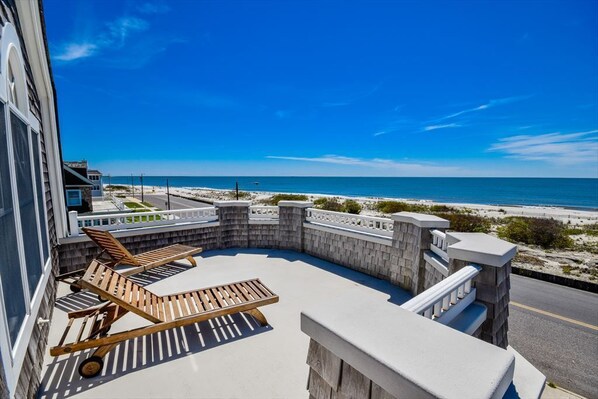 Expansive oceanfront balcony with lounge seating, offering uninterrupted panoramic views of the coastline.