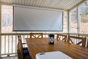 Our outdoor dining area by the screened porch is perfect for meals with a view, and the projector lets you enjoy movies outdoors for the ultimate experience. 