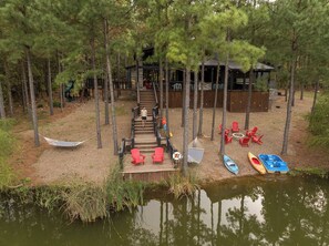 A closer look at the cabin’s private lake access, complete with kayaks, a paddle boat, and red Adirondack chairs by the firepit. A dream location for fishing, paddling, or simply unwinding by the water.