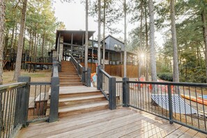 A gorgeous lakeside view of the cabin with a grand wooden staircase leading to the spacious outdoor deck. The perfect spot to enjoy your morning coffee while soaking in the beauty of nature.