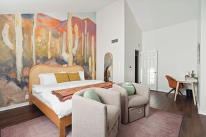 Primary bedroom with King Sized bed, Desk, 2 chairs, and ensuite bathroom with walk in closet
