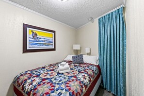 Cozy bedroom with vibrant quilt bedding and beach-themed decor.