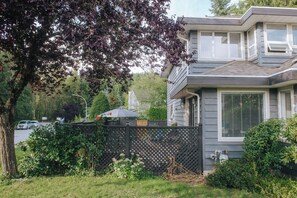 Side patio with comfortable seating areas, dining table, and natural gas BBQ