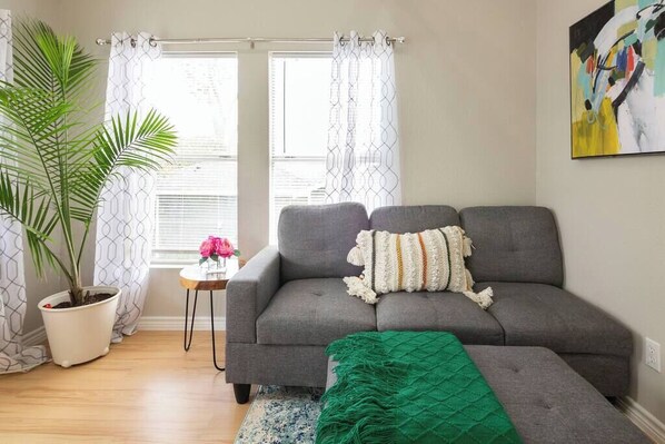 Living Room 1 with a comfy couch. Artwork and lots of natural light.