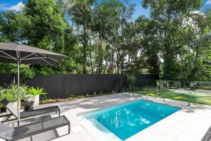 A 4.6 x 2.5-meter plunge pool with two sun lounges and a large umbrella