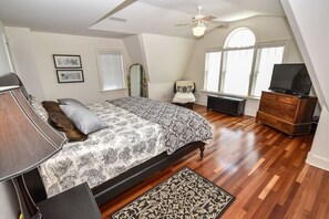 A spacious and elegant king bedroom with abundant natural light and refined furnishings.