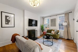 Living room with flat screen smart TV and plenty of seating. Fold out cots offer space for 2 more people to sleep