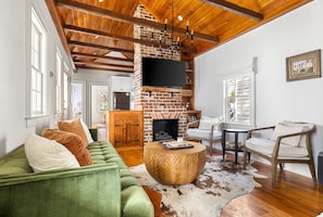 A spacious living room with a lush green velvet couch and a striking brick fireplace, creating the perfect blend of comfort and character.