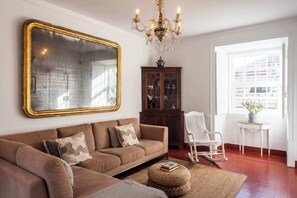 Santo Antonio 2 spacious living room, bathed in natural light, showcasing a large ornate mirror and a cozy sectional sofa.