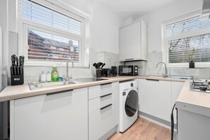 A well-equipped kitchen with all the essentials, including an oven, cooker, pots, microwave, toaster, and a coffee machine—perfect for preparing meals with ease and convenience.