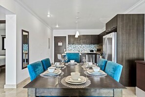 - Dining space set for an elegant meal, with vibrant blue chairs adding a pop of color - Open layout seamlessly connects to the kitchen, perfect for hosting and entertaining - Modern lighting and stylish table settings complete the inviting ambiance