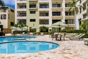 A tranquil shared pool area surrounded by palm trees and modern apartments.
