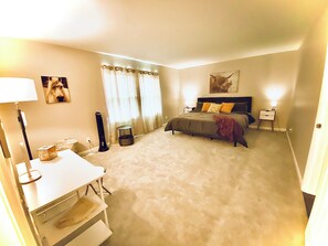 Master suite with king bed and vanity with stool and hair dryer.
