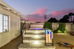 Enjoy the ultimate backyard retreat with a hot tub, corn hole, covered patio, BBQ, and fire pit for endless relaxation and fun.