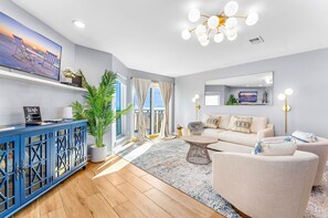 The living room features a sofa that transforms into a comfortable Queen Sleeper, complemented by two stylish swivel chairs.