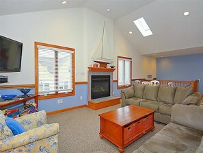 Inviting family room with comfortable seating, a fireplace, and a vaulted ceiling, offering a cozy space to unwind.