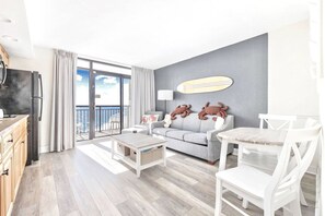 Charming 1BR oceanfront getaway with a serene beach cove setting. The living room offers comfy seating, elegant decor, and expansive windows with ocean vistas. Relax on the private balcony as the gentle sound of waves creates a peaceful ambiance.