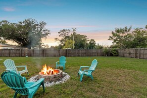 Private backyard fire pit in Clearwater with turquoise Adirondack chairs and sunset views for group gatherings 