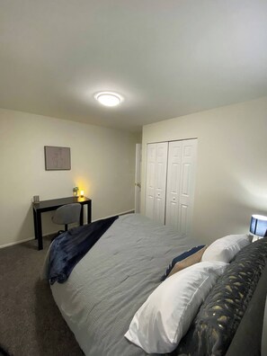 The largest bedroom features a workspace equipped with a comfortable rolling chair, desk, light and pen holder. 