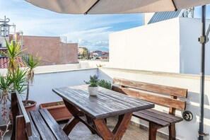 The roof terrace of Casa Eleni features a dining table for outdoor meals and a washing machine for convenience, all set against an open-air backdrop.