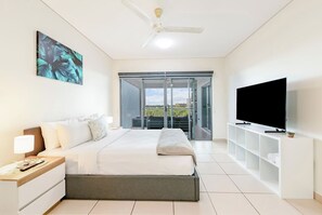 The primary suite extends to the balcony, set with a queen bed and flat screen TV.