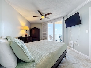Relaxing bedroom featuring a comfortable bed, flat-screen TV, and direct balcony access, offering breathtaking ocean views and a serene coastal ambiance.