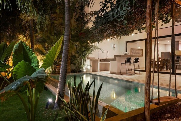 Beautiful outdoor bar for enjoyment, well-lit next to the pool.
