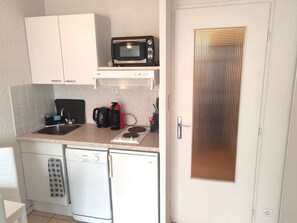Prepare your favourite dishes in this compact yet fully equipped kitchenette, offering essential appliances like a microwave, stove, and refrigerator, plus a convenient layout for easy cooking.