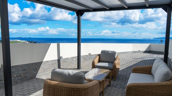 Relax on the stylish patio of Ozeanica Heights by LovelyStay, featuring a cozy lounge under a pergola. Enjoy stunning ocean views, the Desert Islands, and a distant glimpse of the airport.. #oceanview #santacruz #desertislands #madeira