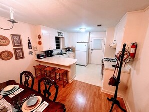 Stools at counter, gas range, microwave, toaster oven, coffee maker.